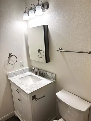 a bathroom with a granite countertop sink toilet and mirror