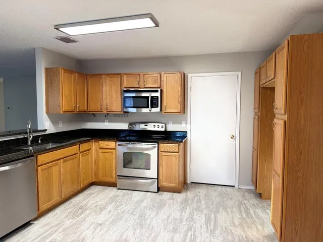 a kitchen with stainless steel appliances granite countertop a stove a sink and a refrigerator