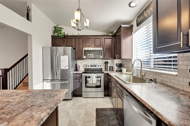 a kitchen with stainless steel appliances granite countertop a sink refrigerator stove and microwave