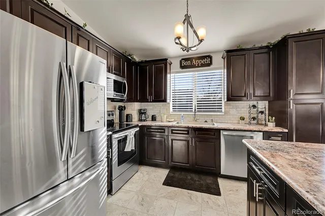 a kitchen with stainless steel appliances granite countertop a refrigerator a stove a sink dishwasher a oven with wooden cabinets and chairs