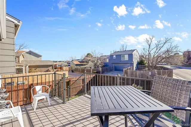 a view of a roof deck with table and chairs with wooden floor and fence