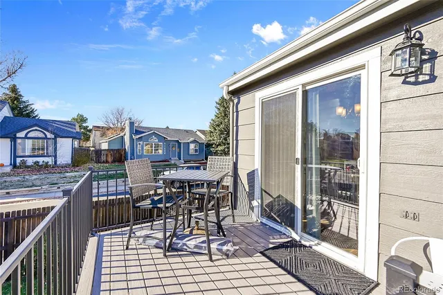 a view of a patio with table and chairs with wooden floor and fence