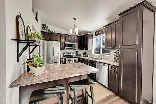 a kitchen with stainless steel appliances wooden floor dining table and chairs