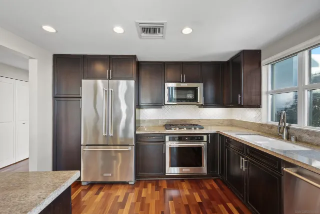 a kitchen with granite countertop a refrigerator a stove top oven and sink