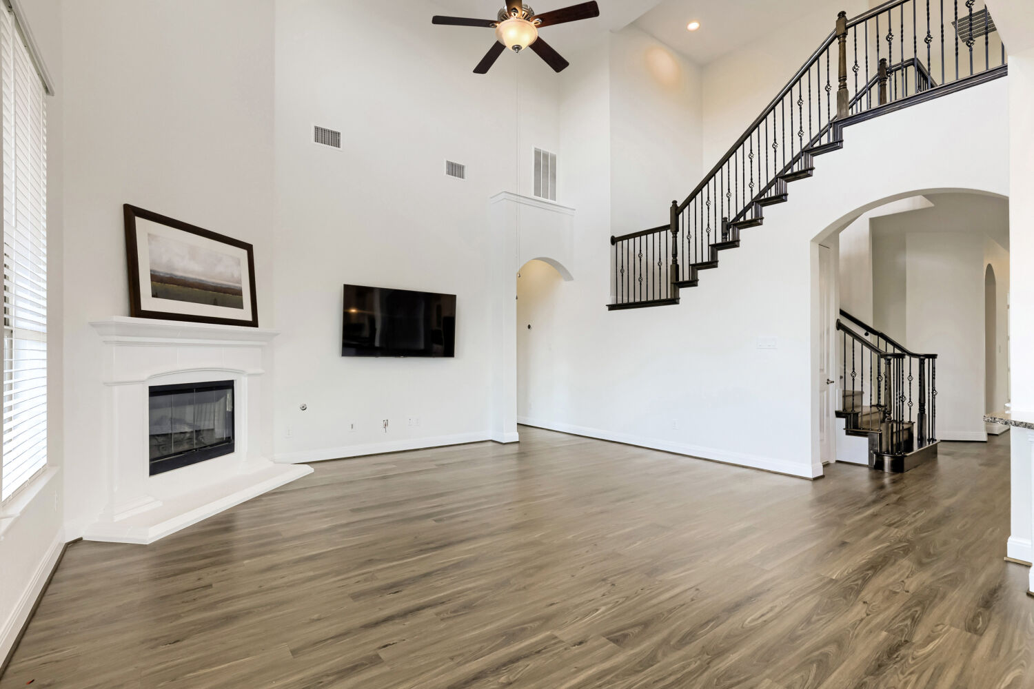 19205 Burrowbridge Road Pflugerville, TX 78660 - Photo 9 of 38 A spacious living room features soaring ceilings and elegant flooring, with a cozy fireplace at its heart.