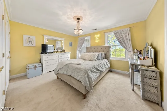a bedroom with a bed a chandelier and dresser