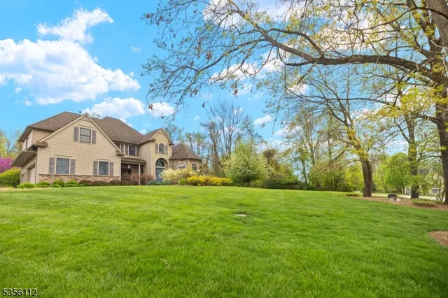 a view of a white house in front of a big yard with large trees