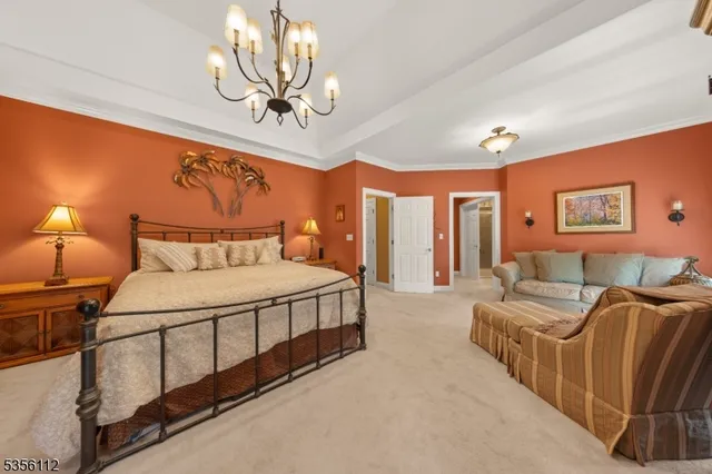 a spacious bedroom with a bed a chandelier and glass door