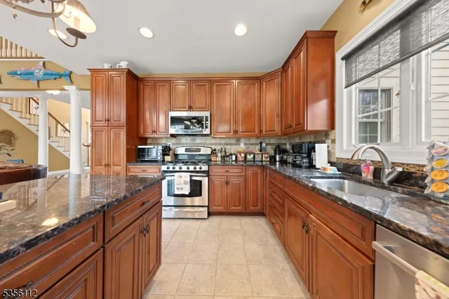 a kitchen with stainless steel appliances granite countertop a stove a sink dishwasher and a microwave oven with cabinets