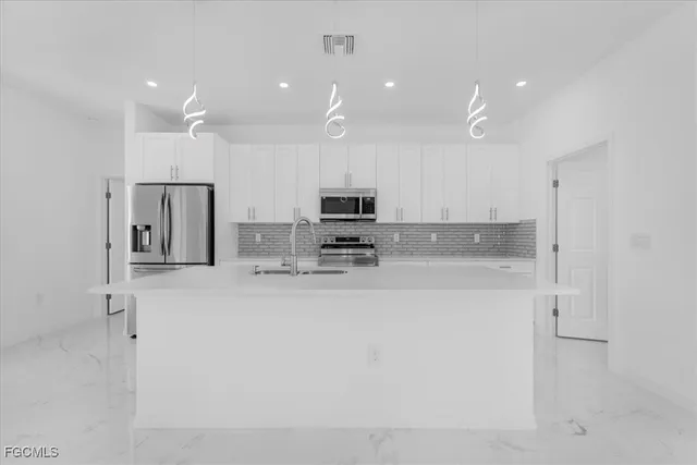 a view of kitchen with kitchen island a sink stainless steel appliances and cabinets