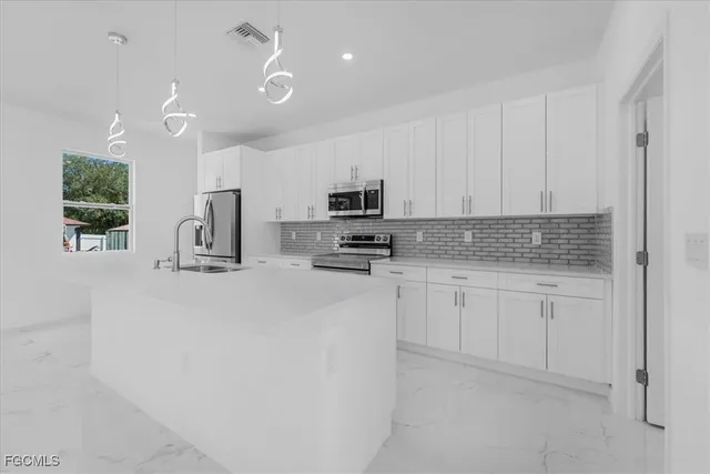 a kitchen with granite countertop white cabinets and stainless steel appliances