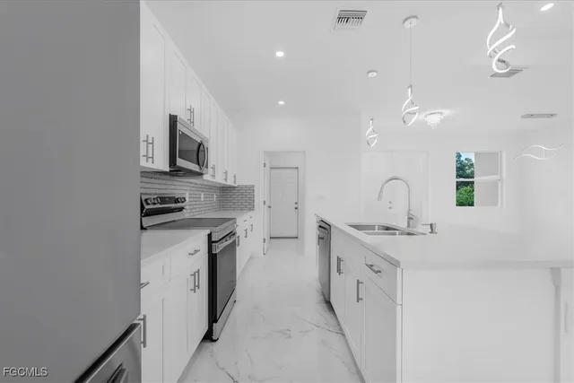 a large kitchen with kitchen island a sink stainless steel appliances and cabinets