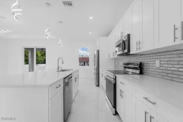 a kitchen with stainless steel appliances granite countertop a sink a stove and a refrigerator