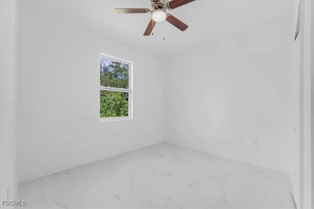 an empty room with a ceiling fan and a window