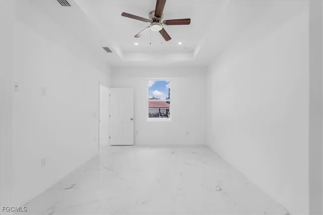 an empty room with a ceiling fan and window