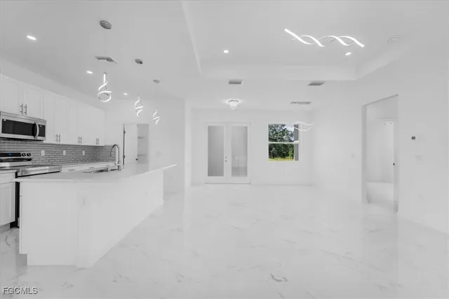 a large white kitchen with kitchen island a sink stainless steel appliances and cabinets