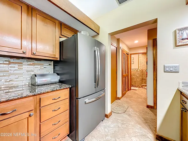 a kitchen with granite countertop a refrigerator and cabinets