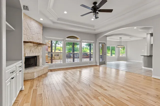 a view of an empty room with wooden floor and a fireplace