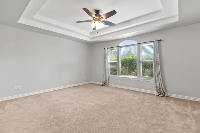 an empty room with windows and ceiling fan
