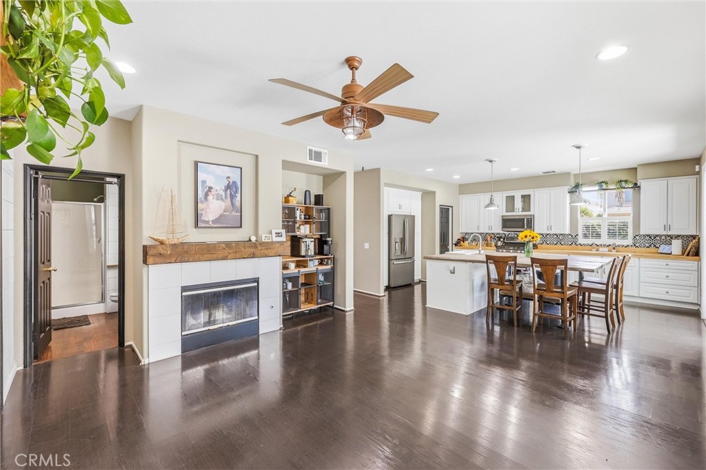 8402 Lindenhurst Street Riverside, CA 92508 - Photo 14 of 60 a living room with furniture a fireplace and a dining table with wooden floor