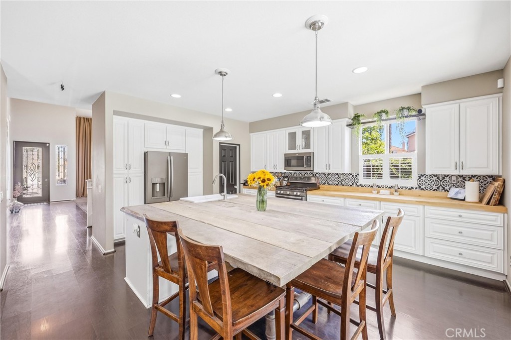 8402 Lindenhurst Street Riverside, CA 92508 - Photo 16 of 60 a kitchen with stainless steel appliances kitchen island granite countertop a dining table chairs and white cabinets