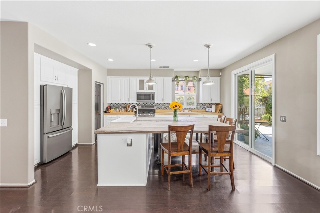 8402 Lindenhurst Street Riverside, CA 92508 - Photo 2 of 60 a kitchen with stainless steel appliances a dining table chairs and wooden floor