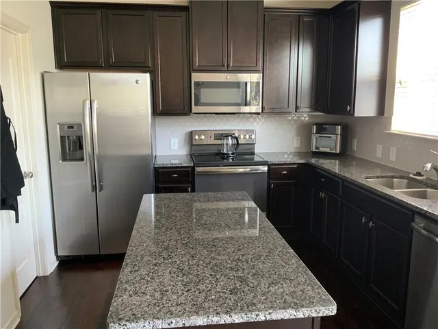 a kitchen with stainless steel appliances granite countertop a refrigerator stove and sink