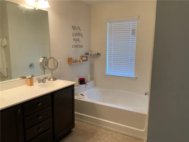 a bathroom with a tub sink and mirror