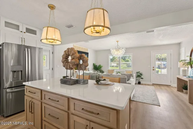 a living room with furniture kitchen view and a chandelier