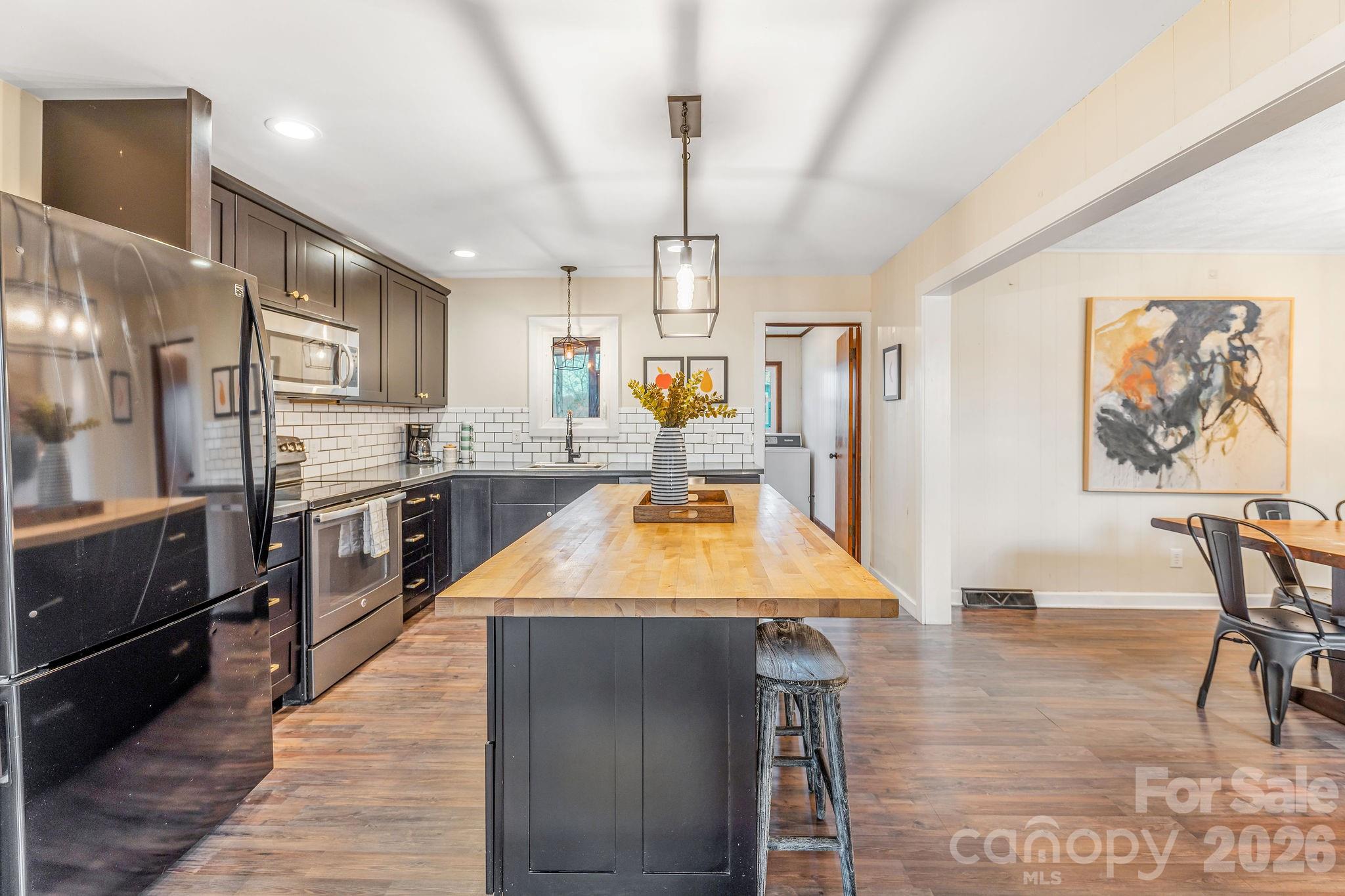 96 Oak Hill Road Candler, NC 28715 - Photo 8 of 41 a kitchen with stainless steel appliances granite countertop a refrigerator a sink dishwasher a stove and a dining table with wooden floor