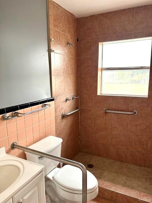 1317 South B Street Harlingen, TX 78550 - Photo 7 of 10 a bathroom with a granite countertop toilet a sink a mirror and a window