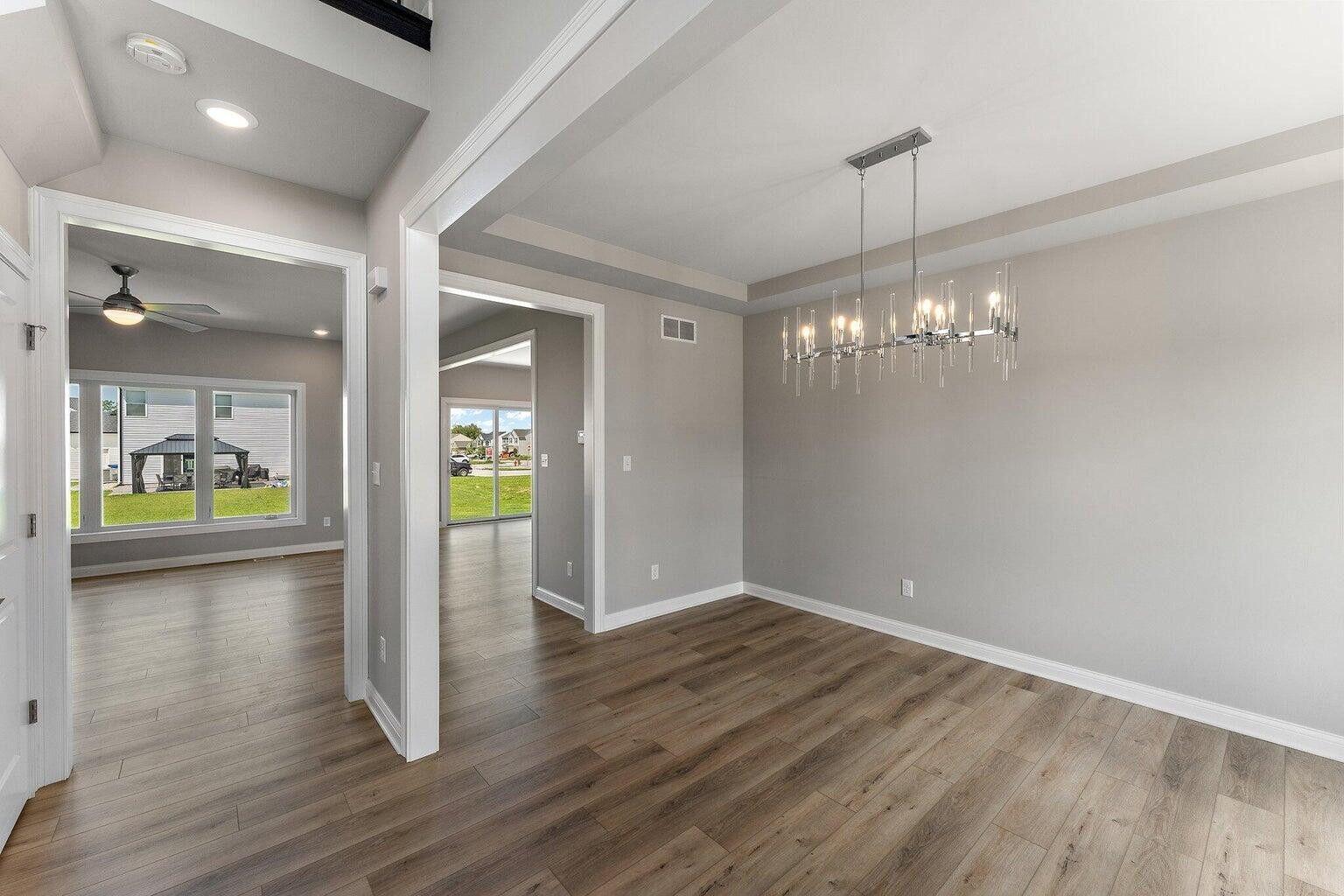 3090 West 105th Avenue Crown Point, IN 46307 - Photo 2 of 22 a view of a hallway with wooden floor and a chandelier