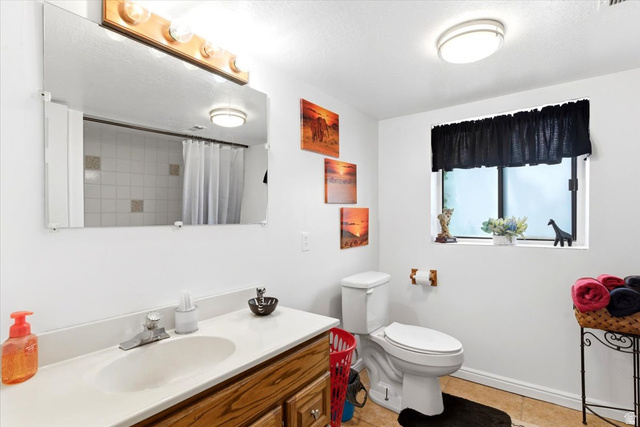 5321 South 3100th Street West Roy, UT 84067 - Photo 55 of 64 Bathroom with a single vanity featuring a wood-finish cabinet and a white countertop