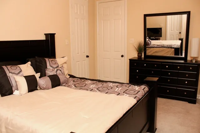 a bedroom with a bed and a flat tv screen on dresser