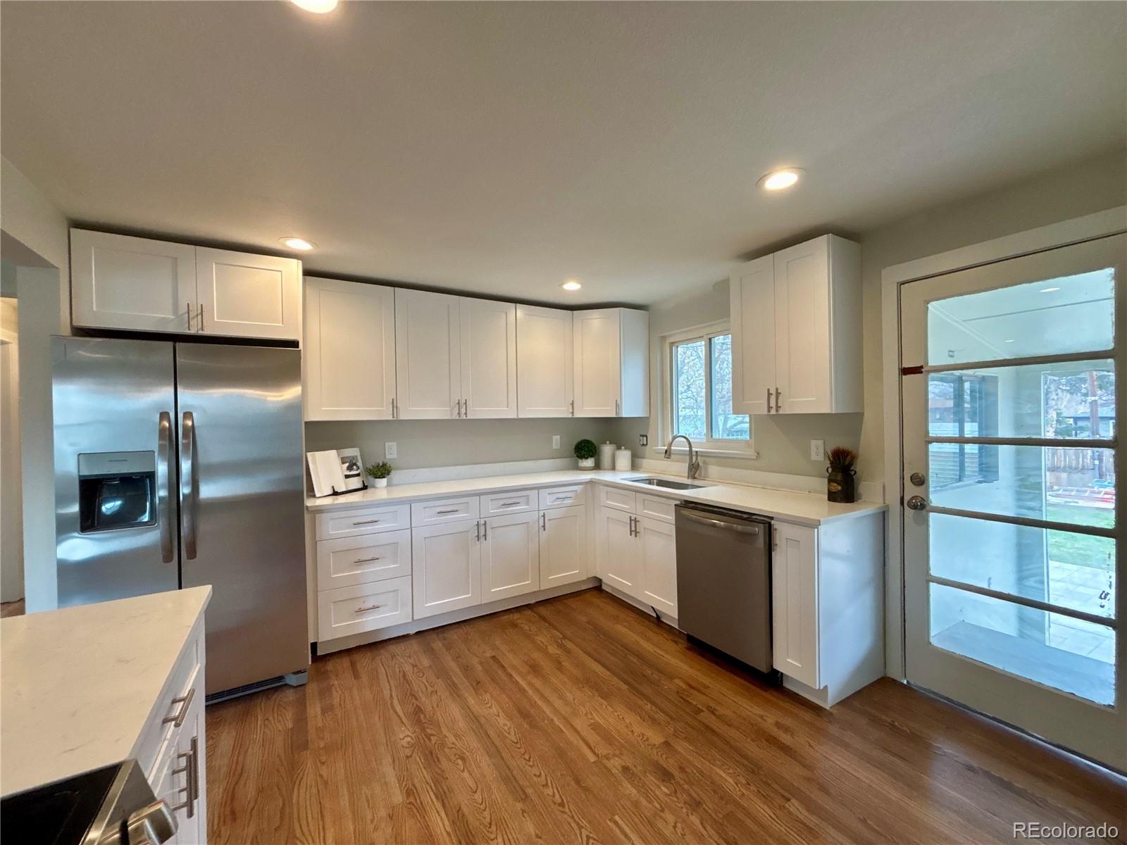 4420 Teller Street Wheat Ridge, CO 80033 - Photo 6 of 20 a kitchen with a sink cabinets stainless steel appliances and wooden floor
