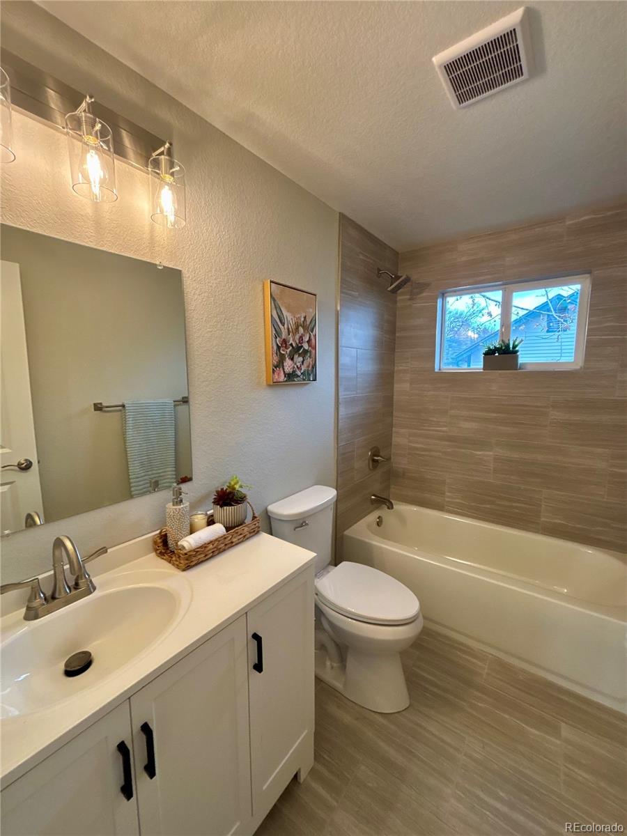 4420 Teller Street Wheat Ridge, CO 80033 - Photo 10 of 20 a bathroom with a double vanity sink toilet and a bathtub