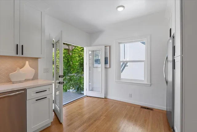 a kitchen with white cabinets and wooden floor