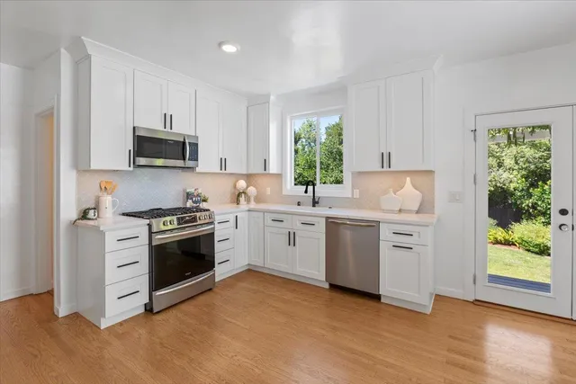 a kitchen with white cabinets and appliances