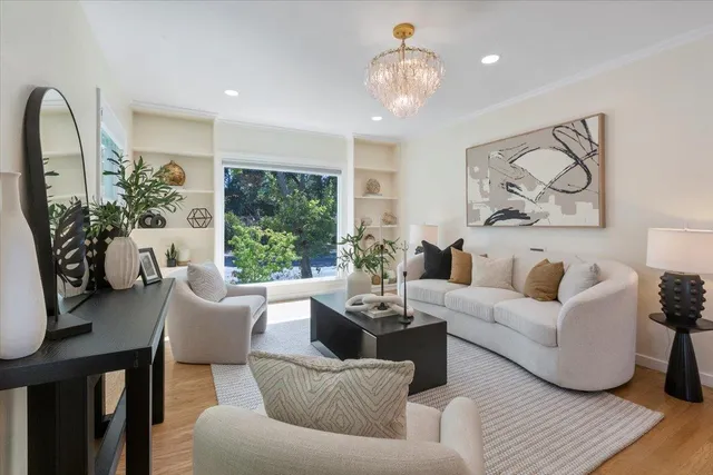 a living room with furniture a large window and a chandelier