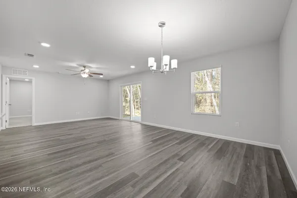 a view of kitchen and empty room with wooden floor