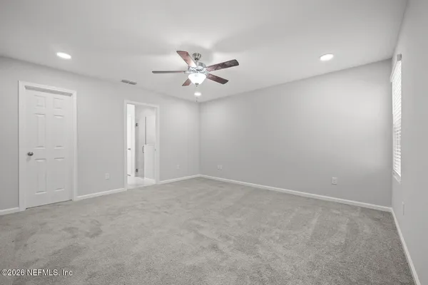 an empty room with closet and a ceiling fan