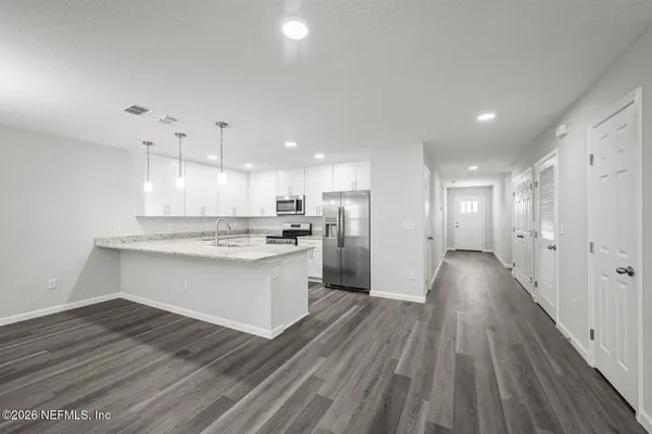 a large kitchen with stainless steel appliances granite countertop a sink a stove and a wooden floors