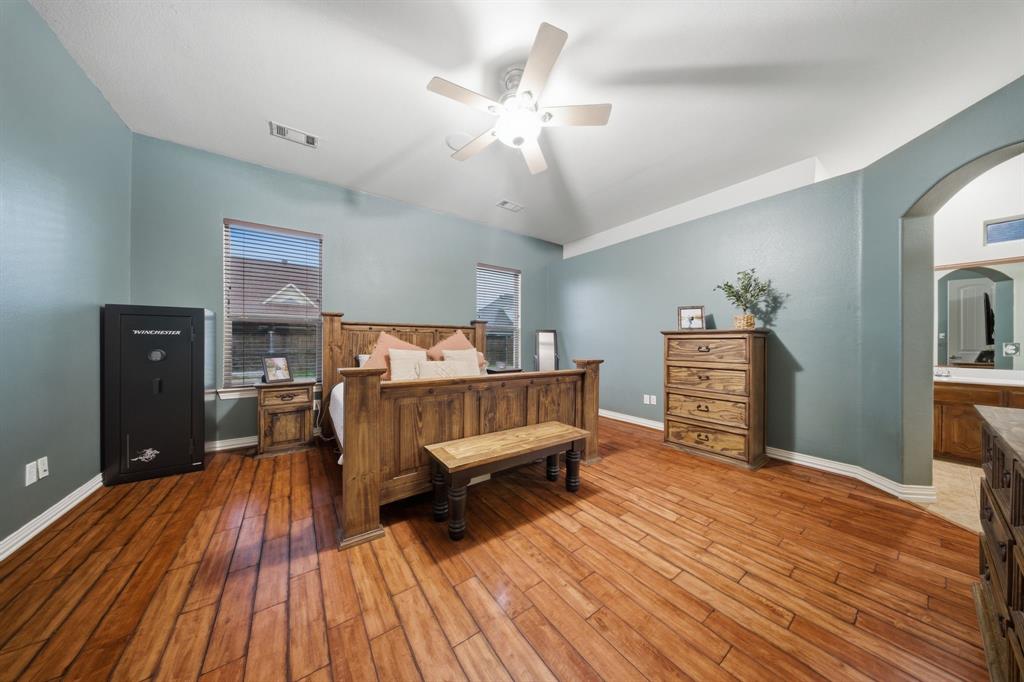 603 Cedar Drive Pilot Point, TX 76258 - Photo 14 of 39 Wood-finish flooring throughout, featuring a vaulted ceiling with a ceiling fan, two windows with blinds, and an arched entryway to an adjoining space