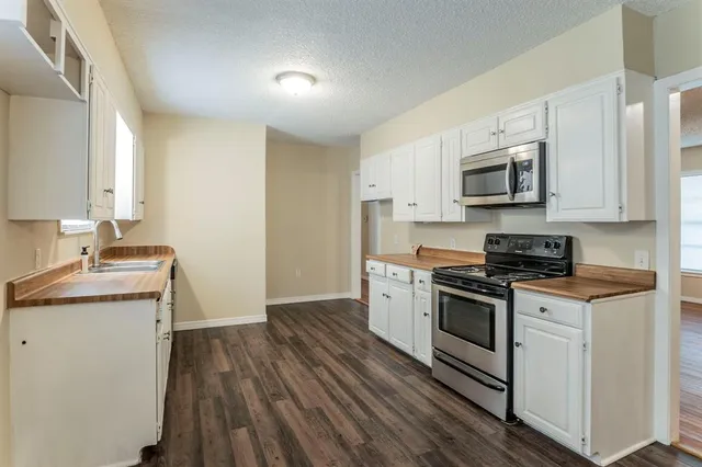 a kitchen with stainless steel appliances granite countertop a stove top oven a sink a microwave oven with cabinets and wooden floor