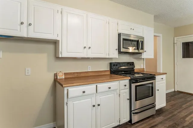 a kitchen with stainless steel appliances granite countertop a stove a microwave oven and white cabinets