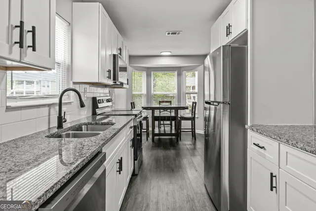 a kitchen with granite countertop a sink stove and cabinets