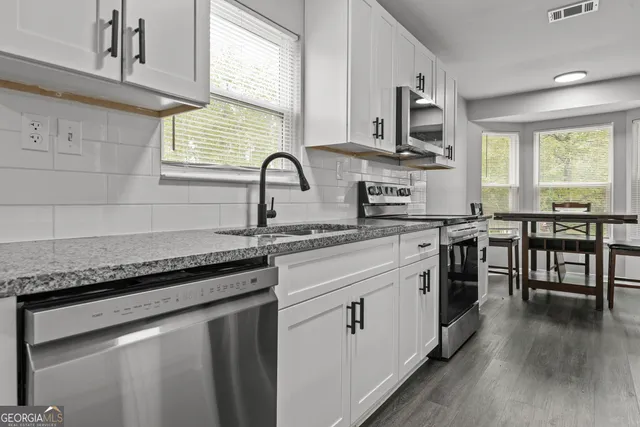 a kitchen with stainless steel appliances granite countertop hardwood floor sink stove dining table and chairs