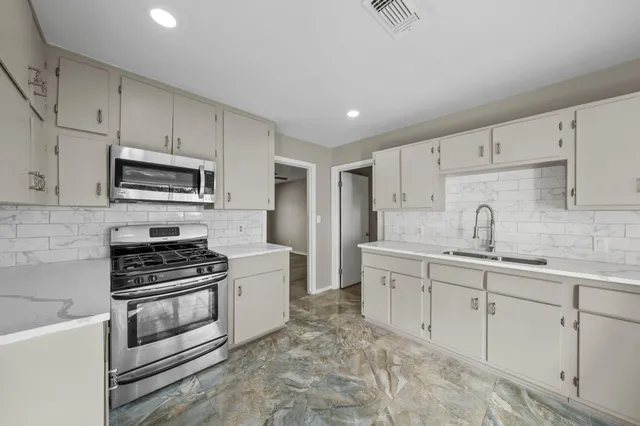 a kitchen with white cabinets stainless steel appliances and a sink