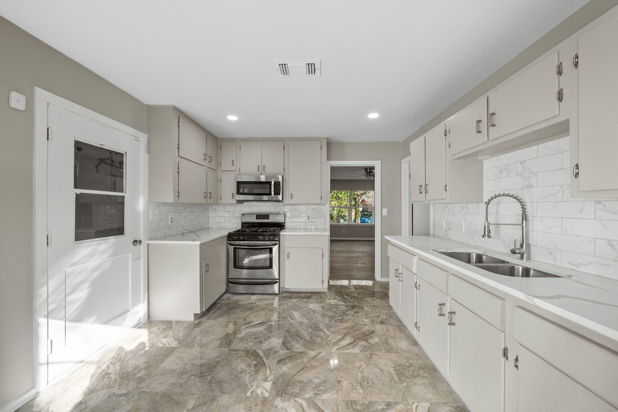 4110 Friar Point Road Houston, TX 77047 - Photo 2 of 15 a large white kitchen with stainless steel appliances granite countertop a sink and cabinets
