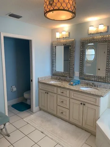 a bathroom with a granite countertop sink mirror bathtub and next to a window
